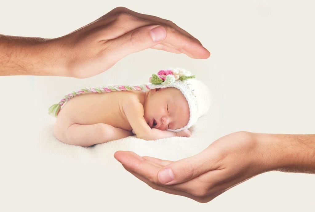 赤ちゃんを手で囲む画像