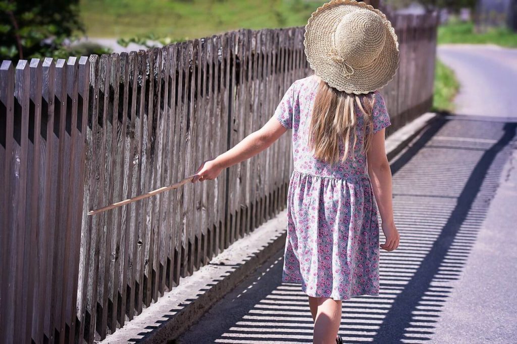 麦わら帽子をかぶった女の子が歩いている画像